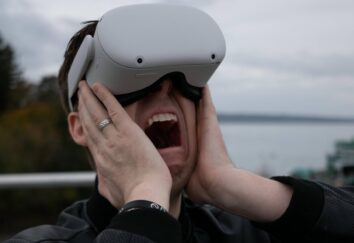 A man in a denim jacket is screaming and wearing VR glasses