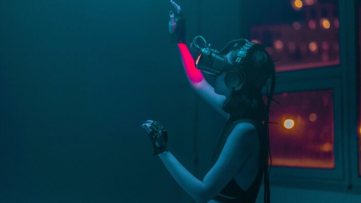 A woman with a long plait and VR glasses reaches up to touch a virtual object