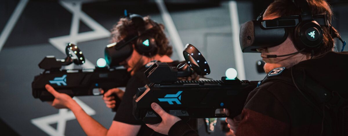 Landscape image of two men engrossed in a VR shooting game